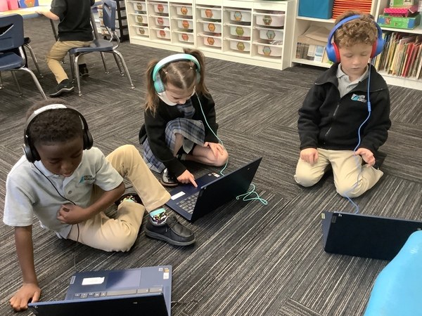 FAITH Academy students working on laptops with headphones
