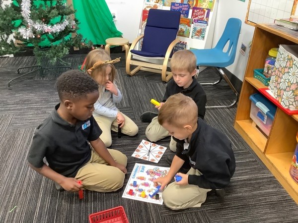 FAITH Academy students playing a learning game together on the classroom floor